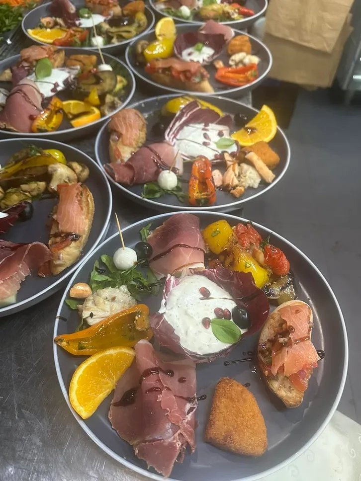Runde Teller mit Parmaschinken, Burrata, Lachs-Crostini, Oliven und Orangenspalten