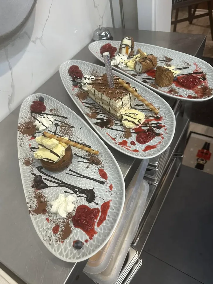 Drei Dessertteller mit Törtchen, Sahne und Fruchtspiegel