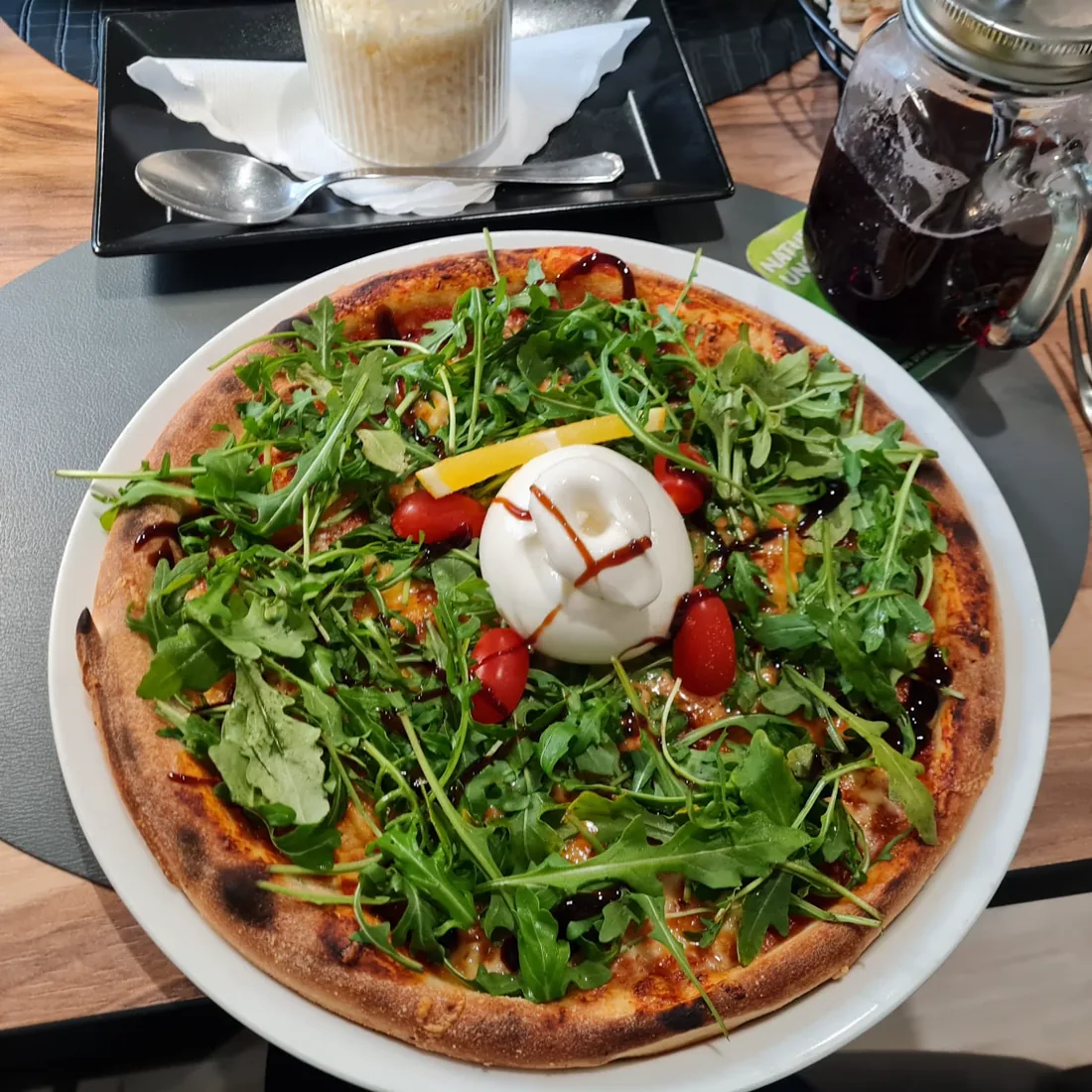 Pizza aus dem Steinofen mit Rucola, Burrata, Kirschtomaten und Balsamico